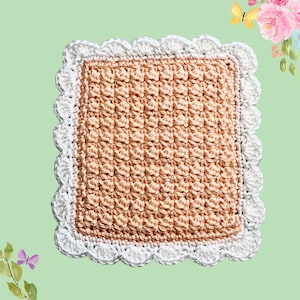May include: A square, handmade crochet item with a textured, peach-colored center and a white scalloped border. The crochet pattern creates a raised, dimensional effect. The item is likely a coaster or decorative piece.