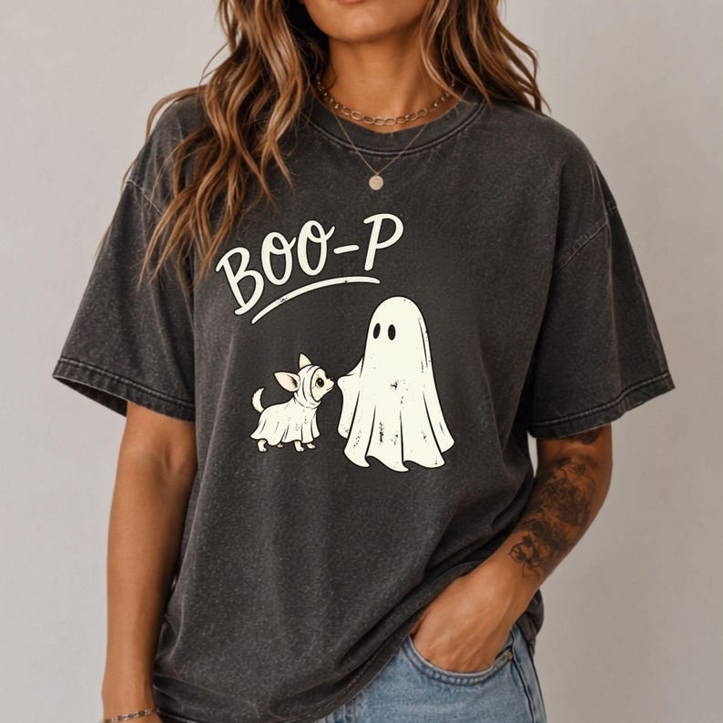 May include: A charcoal grey short-sleeve t-shirt featuring a graphic print of a small dog in a ghost costume standing next to a larger ghost figure. The text BOO-P is printed in white above the figures. The shirt has a faded, vintage-style texture.