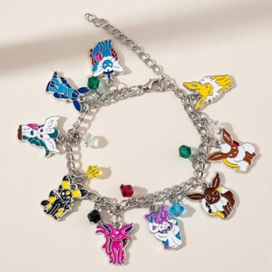 May include: A silver charm bracelet with colourful enamel charms depicting cartoon characters. The charms are in shades of blue, yellow, pink, and brown, with small, colourful beads along the chain.