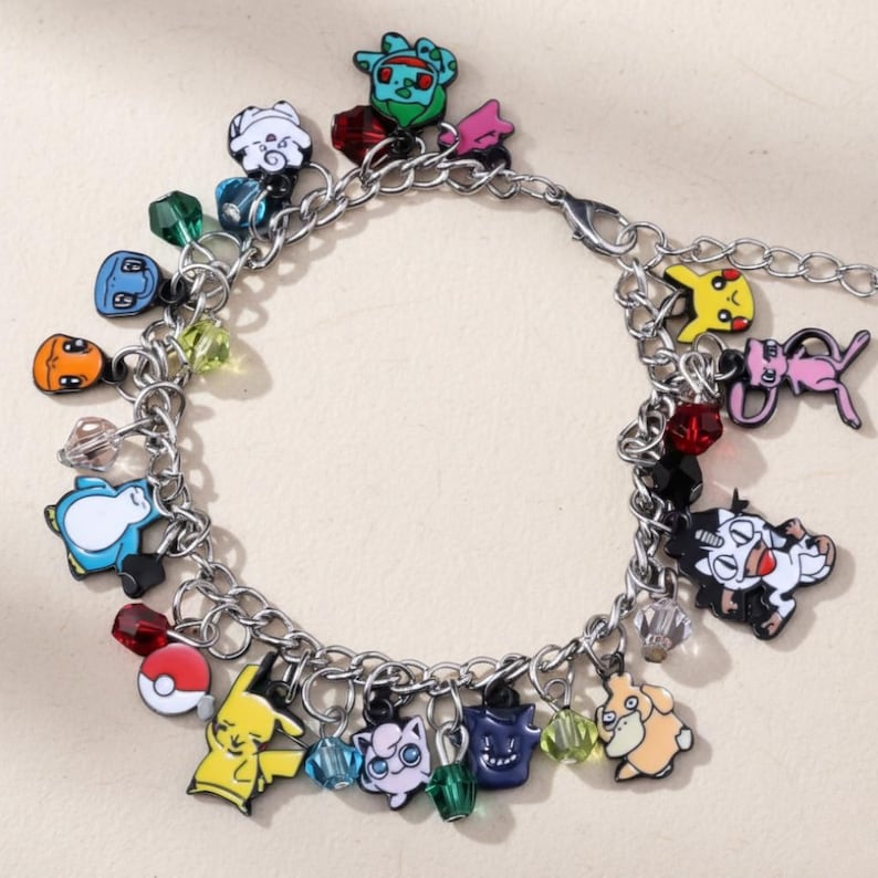 May include: Silver charm bracelet with cartoon character charms in various colours. The bracelet features yellow, blue, and pink charms, alongside clear and coloured bead accents. The charms are connected by a silver chain.