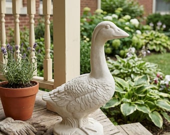 May include: A light-colored, off-white goose figurine standing on a textured base. The sculpture features detailed feather carvings across its body, a long neck, and a smooth head. It is positioned on a wooden surface alongside a small metal key.