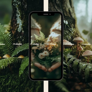 May include: A close-up of a phone screen displaying a photo of a hand holding a bouquet of white mushrooms and ferns in a forest setting. The background is blurred and green.