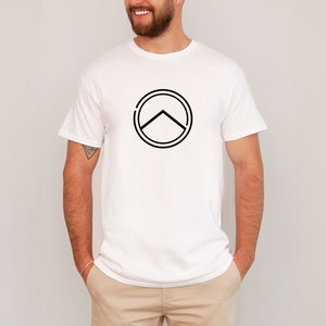 Könnte beinhalten: Weißes T-Shirt mit einer schwarzen Grafik eines spartanischen Schildes.