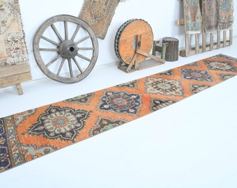 May include: A long, orange runner rug with a traditional Persian design. The rug has intricate floral patterns in shades of blue, green, and cream.