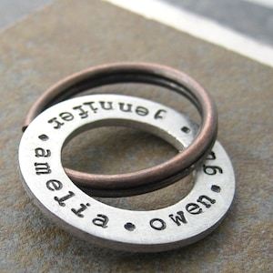 May include: A silver metal keychain with two rings. The larger ring has the names "Amelia" and "Owen" engraved on it. The smaller ring has the name "Jennifer" engraved on it.