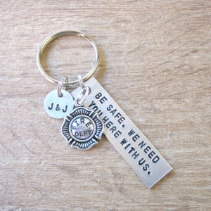 May include: Silver keychain with a firefighter charm, a small round charm with the initials "J&J" and a tag that reads "BE SAFE. WE NEED YOU HERE WITH US."