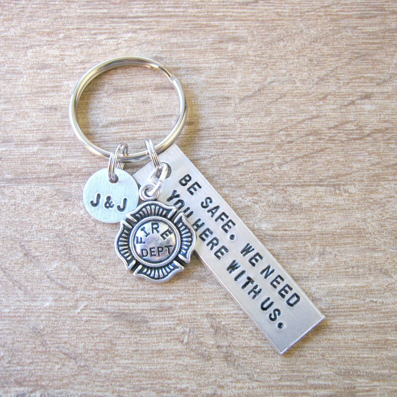 May include: Silver keychain with a firefighter charm, a small round charm with the initials "J&J" and a tag that reads "BE SAFE. WE NEED YOU HERE WITH US."
