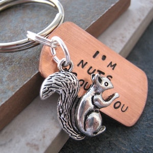 May include: A copper keychain with a silver squirrel charm. The keychain has the text "I'm nuts about you" engraved on it.