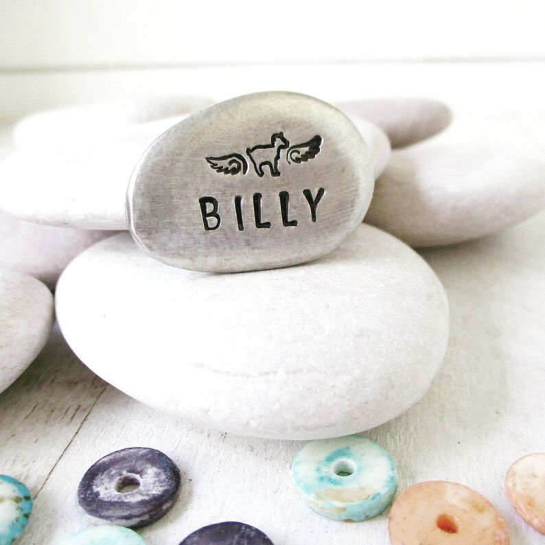 May include: A silver metal memorial stone with a paw print and wings design. The stone is engraved with the name "BILLY".