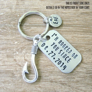 May include: Silver keychain with a fish hook charm and a tag that reads "I'm hooked on you since 08.27.2014".