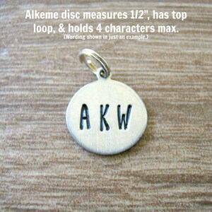 May include: A small, silver disc pendant with the letters "AKW" stamped on it. The disc has a top loop and measures 1/2 inch. The text "Alkeme disc measures 1/2", has top loop, & holds 4 characters max." is above the pendant.