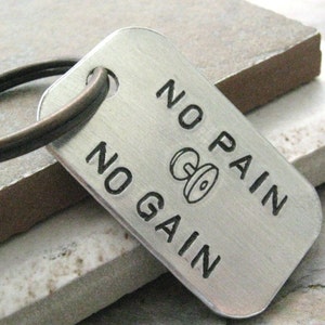 May include: Silver keychain with a dumbbell graphic and the text "No Pain No Gain".