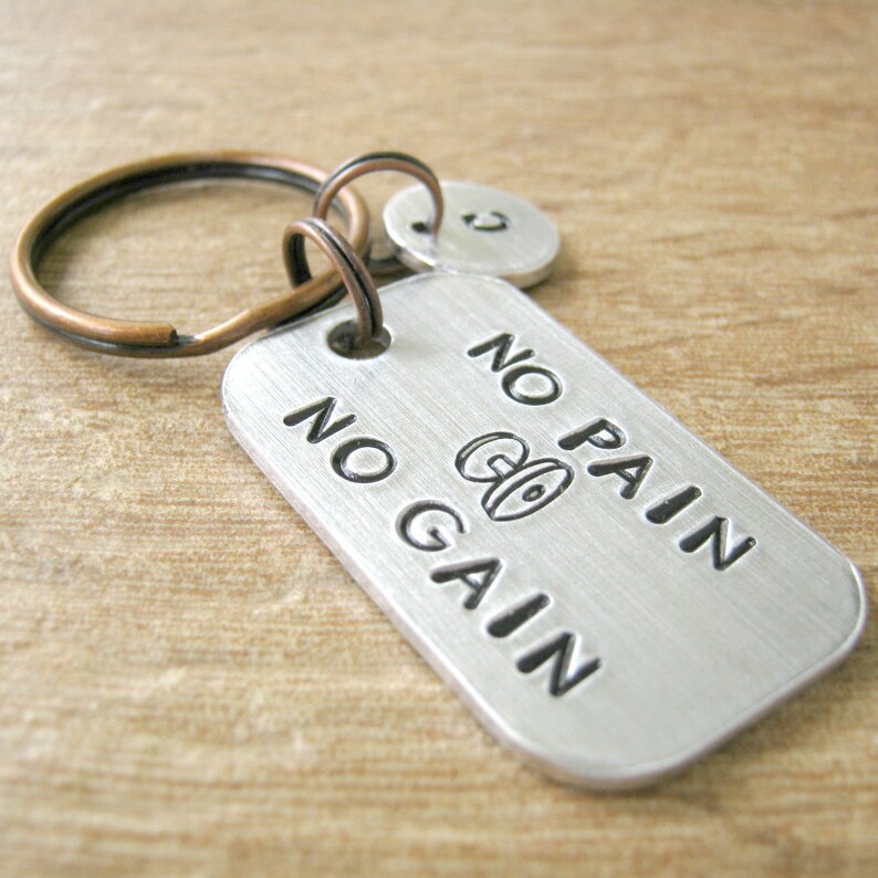 May include: Silver keychain with a copper key ring and a silver tag that says "No Pain No Gain" with a dumbbell icon.