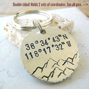 May include: Silver keychain with a round tag engraved with coordinates "36°34′43″N 118°17′32" W" and a mountain range design.