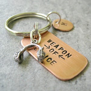 May include: A copper keychain with a silver charm of headphones and the text "Weapon of Choice".