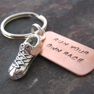 May include: Silver running shoe charm attached to a copper key chain with the text "Run Your Own Race".