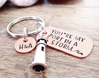 May include: A copper keychain with a lighthouse charm and a tag that reads "You're my port in a storm". The tag also has a small wave design. The keychain also has a smaller copper tag with the initials "H&A" engraved on it.