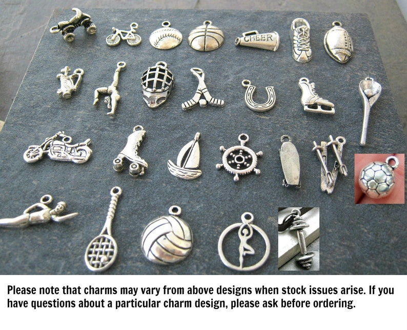 May include: A collection of silver charm pendants featuring various sports and activities, including a basketball, football, sailboat, roller skates, and a motorcycle.  The charms are displayed on a dark gray background.
