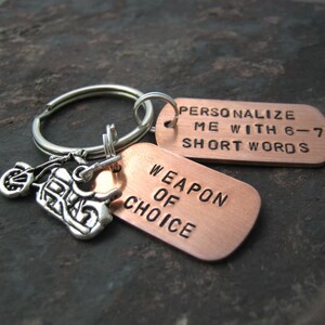 May include: Copper keychain with a motorcycle charm and two tags. The larger tag reads "Weapon of Choice". The smaller tag reads "Personalize me with 6-7 short words".