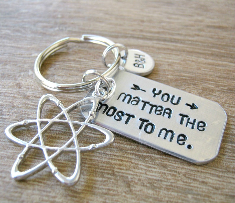May include: Silver-colored keychain with a tag that reads "you matter the most to me." The keychain includes a charm shaped like an atom and a small circular tag with the initials "B&H."