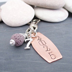 May include: A copper keychain with a graduation cap design and the year 2025 engraved on it. The keychain also features a silver charm with the number 7 and a purple lava rock bead.