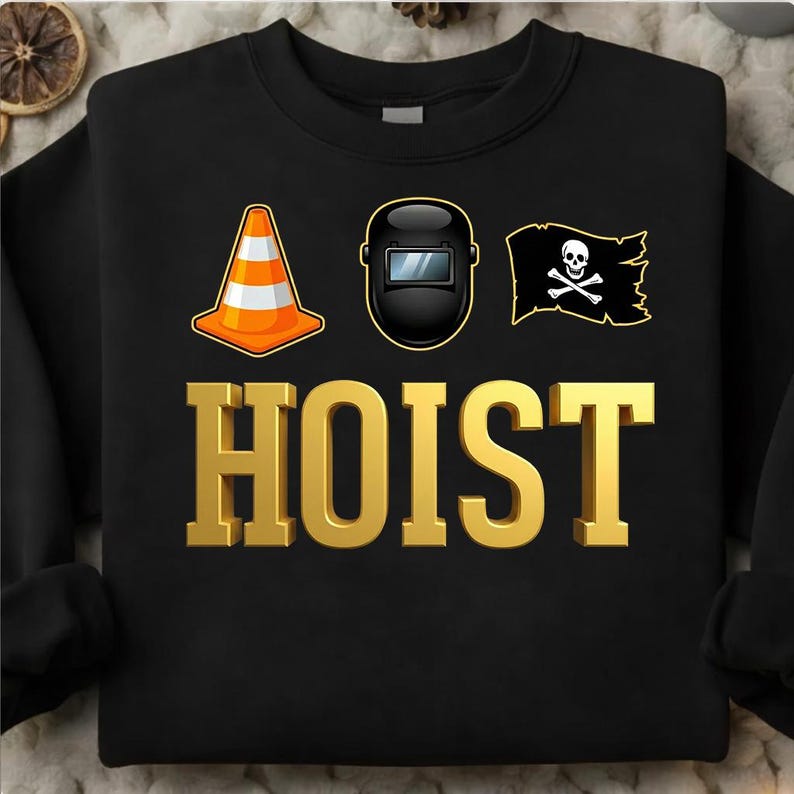 May include: Black sweatshirt with a gold "HOIST" text and three graphics: an orange and white traffic cone, a black welding mask, and a black pirate flag with a skull and crossbones. The sweatshirt is a crew neck.