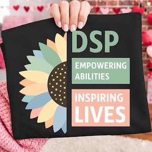 May include: Black t-shirt with a sunflower design on the left. The right side has the letters "DSP" above the words "EMPOWERING ABILITIES" and "INSPIRING LIVES" in a rectangular box. The design is in pastel colours.