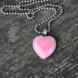 May include: A silver chain necklace with a pink heart-shaped pendant.