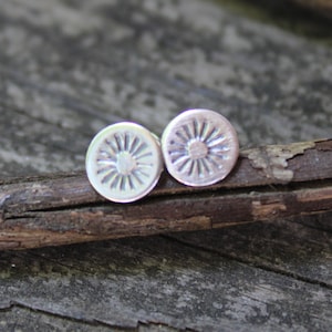 May include: A pair of silver stud earrings with a sunburst design.