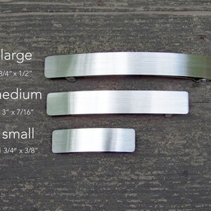 May include: Three silver metal hair clips in different sizes: large (3 3/4 inches by 1/2 inch), medium (3 inches by 7/16 inch), and small (1 3/4 inches by 3/8 inch).