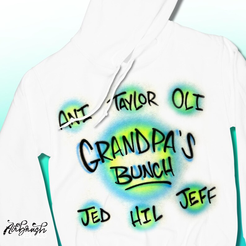 May include: White hoodie featuring airbrushed text and graphics. The design includes the words "GRANDPA'S BUNCH" in a blue and yellow circle, surrounded by names such as "ANT", "TAYLOR", "OLI", "JED", "HIL", and "JEFF".