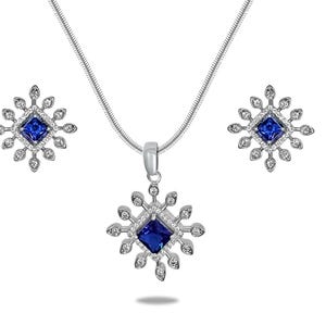 May include: A silver necklace and earrings set with a blue gemstone in the center of each piece. The pendant and earrings are shaped like a snowflake with small clear gemstones around the edges.