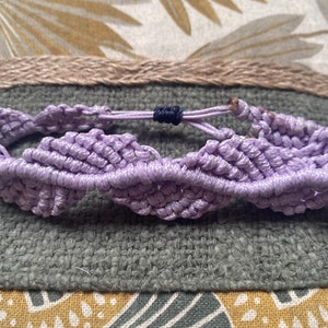 Può includere: Un braccialetto di amicizia intrecciato color lavanda con chiusura regolabile blu scuro.