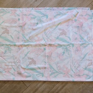 May include: A white cotton pillowcase with a floral pattern featuring pink and green flowers.