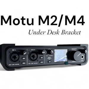 Könnte beinhalten: Schwarzes Motu M2/M4 Audio-Interface mit einem kleinen Bildschirm und Knöpfen. Das Interface ist an einer schwarzen Untertischhalterung montiert.