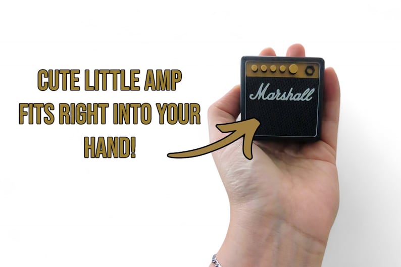 Pu&ograve; includere: Un piccolo amplificatore Marshall nero con manopole dorate e la scritta "Marshall" in lettere bianche. L'amplificatore &egrave; tenuto in mano da una persona.