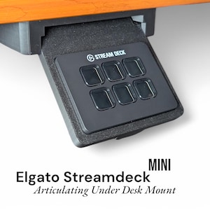 May include: Black Elgato Stream Deck Mini mounted under a desk with six programmable buttons. The Stream Deck Mini is labeled with the text "STREAM DECK".