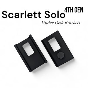 May include: Two black metal brackets designed for mounting under a desk. The brackets have a rectangular shape with a cutout in the centre. The text "4TH GEN" and "Scarlett Solo" are visible in the image.