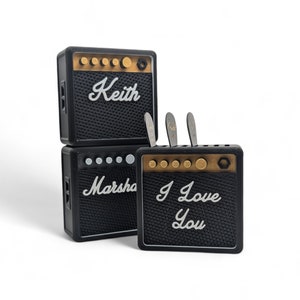 Pu&ograve; includere: Tre mini amplificatori per chitarra neri con dettagli dorati. L'amplificatore superiore ha il nome "Keith" scritto su di esso. L'amplificatore centrale ha il nome "Marsha" scritto su di esso. L'amplificatore inferiore ha le parole "I Love You" scritte su di esso.