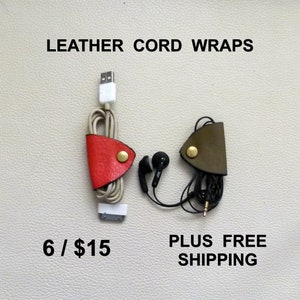May include: Two leather cord wraps, one red and one green, with a gold button closure. The wraps are holding a white USB cable and black headphones. The text "LEATHER CORD WRAPS" is at the top of the image. The text "6 / $15" is at the bottom left of the image. The text "PLUS FREE SHIPPING" is at the bottom right of the image.