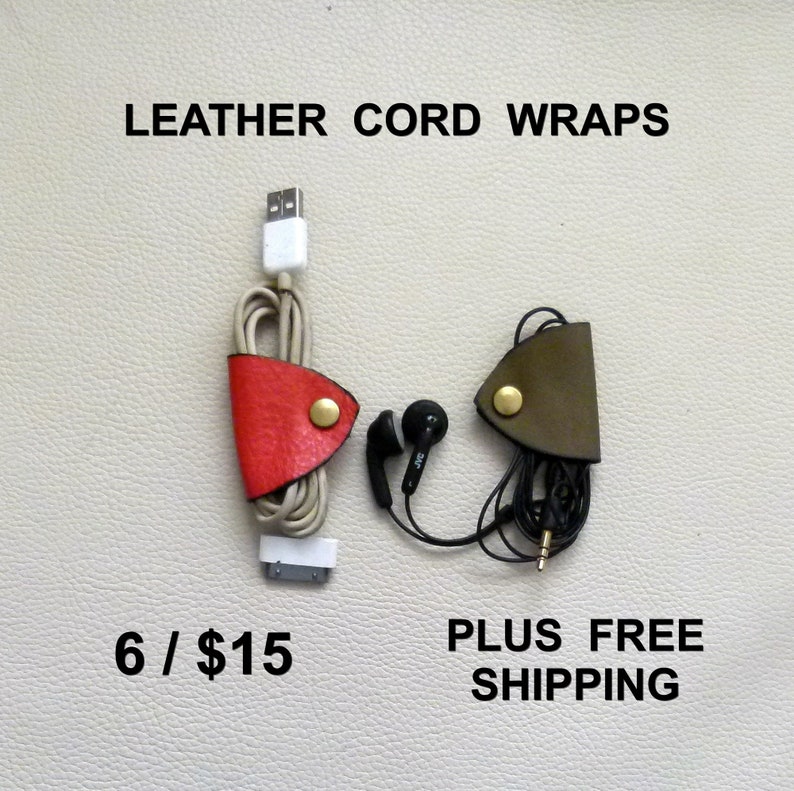 May include: Two leather cord wraps, one red and one green, with a gold button closure. The wraps are holding a white USB cable and black headphones. The text "LEATHER CORD WRAPS" is at the top of the image. The text "6 / $15" is at the bottom left of the image. The text "PLUS FREE SHIPPING" is at the bottom right of the image.