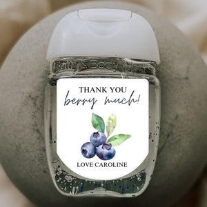 May include: A clear hand sanitizer bottle with a white cap and a label that reads "THANK YOU berry much!" with a watercolor blueberry design. The text "LOVE CAROLINE" is also on the label.