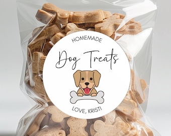 May include: A clear cellophane bag filled with dog treats, tied with a brown ribbon. A round sticker on the bag reads "Homemade Dog Treats" with a cartoon dog and bone graphic, and the text "Love, Kristi."