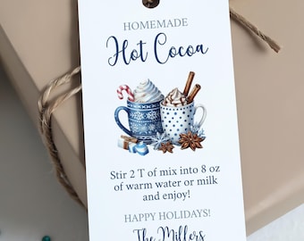 May include: A gift wrapped in tan paper and tied with twine, featuring a white tag. The tag reads "Homemade Hot Cocoa" with an illustration of two mugs of cocoa. The tag also includes instructions and the text "Happy Holidays! The Millers."