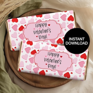 May include: Two printable chocolate bar wrappers with a pink and red heart pattern. The wrappers have a white label with the text "Happy Valentine's Day!" in black.