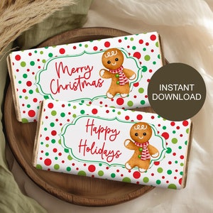 Może przedstawiać: Dwa opakowania czekolady z świątecznymi wzorami. Na jednym napis "Merry Christmas", a na drugim "Happy Holidays". Oba przedstawiają piernikowego ludzika z czerwono-białym szalikiem. Opakowania mają białe tło z czerwonymi i zielonymi kropkami.