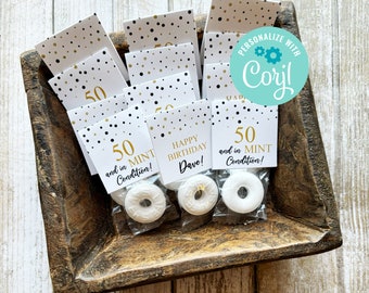 Puede incluir: Una bandeja de bolsas de regalo blancas con diseños de lunares dorados y negros. Las bolsas contienen mentas blancas y tienen el texto "50 and in MINT Condition!" y "Happy Birthday Dave!" impreso en ellas.