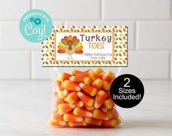 May include: A clear plastic bag filled with candy corn, topped with a rectangular label. The label features a cartoon turkey and the words "Turkey Toes" with "Happy Thanksgiving from Lilly". A black circle indicates "2 Sizes Included!"