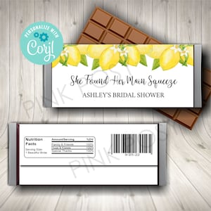 Könnte beinhalten: Ein weißer Schokoladenriegel-Wrapper mit einem Zitronen- und Blumendesign. Der Text auf dem Wrapper lautet "She Found Her Main Squeeze Ashley's Bridal Shower". Die Rückseite des Wrappers zeigt ein Nährwertkennzeichen und einen Barcode.