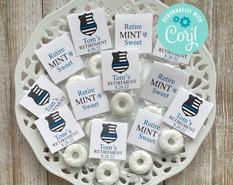 Puede incluir: Un plato blanco con bolsas de regalo azules y blancas llenas de mentas blancas. Las bolsas tienen un diseño de placa de policía azul y blanca con el texto "Tom's Retirement 8.26.22" y "Retire MINT is Sweet".